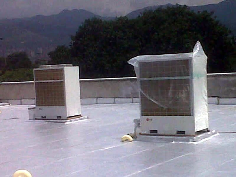 Dos aparatos de aire acondicionado están situados encima de un tejado con montañas de fondo.