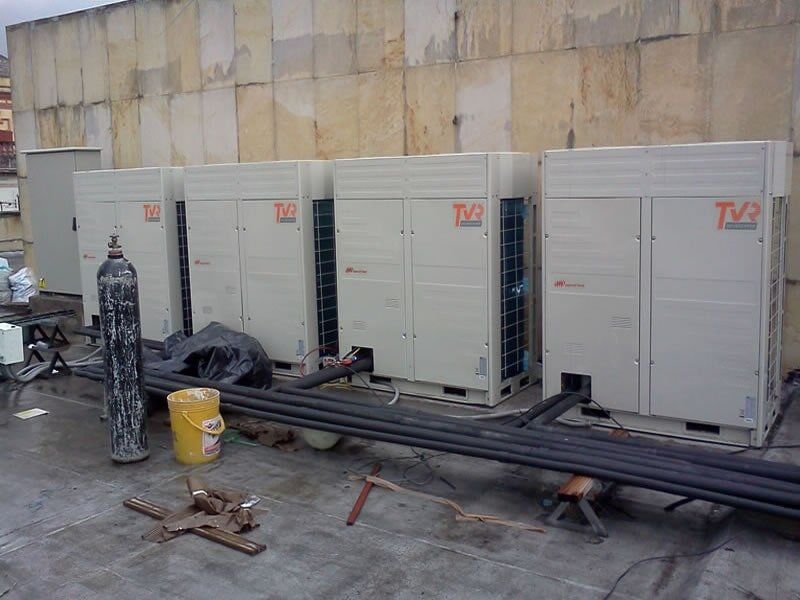 Una fila de aparatos de aire acondicionado están colocados en el techo de un edificio.