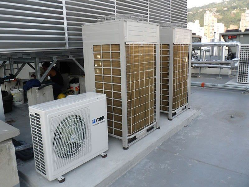 Hay tres aparatos de aire acondicionado instalados en el tejado de un edificio.
