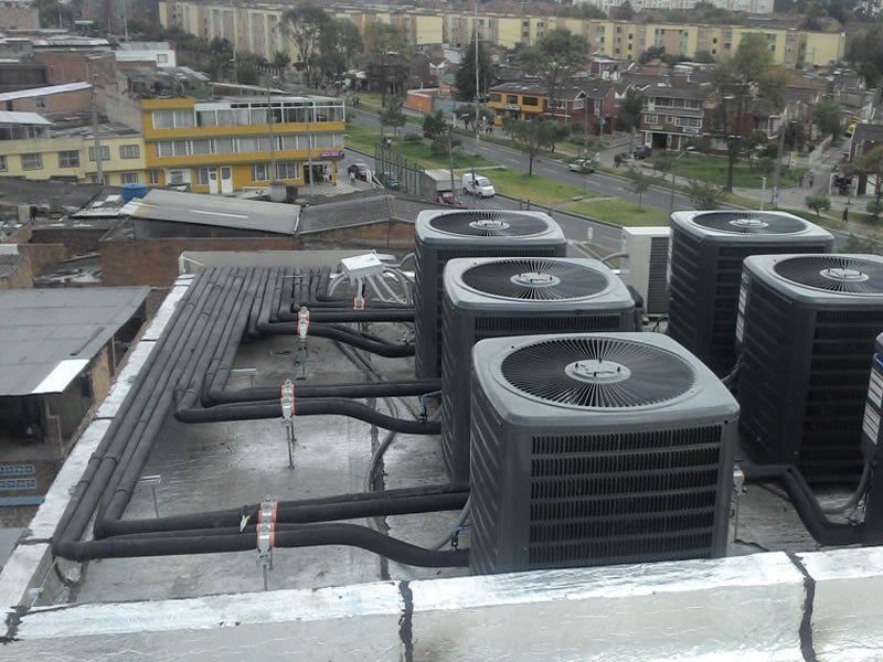 Un montón de aparatos de aire acondicionado están en el techo de un edificio.