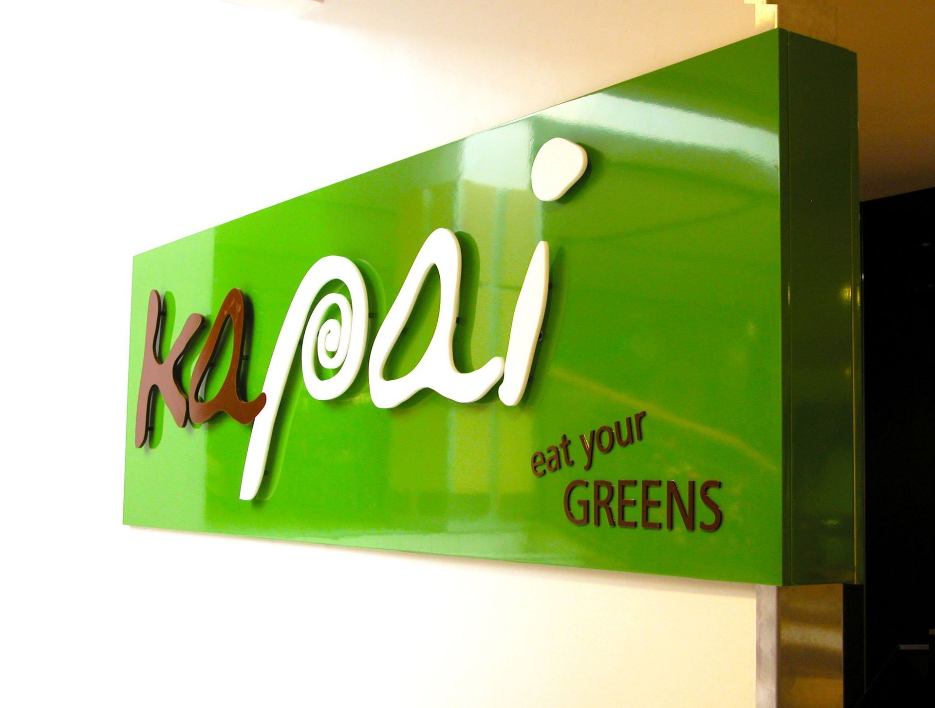 20mm thick router cut acrylic lettering applied onto green backing panel and installed onto shop wall