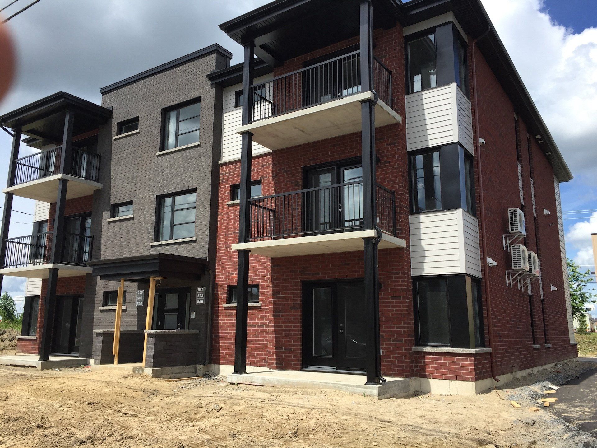 Immeuble d'appartements en briques de plusieurs étages avec balcons et finitions noires.