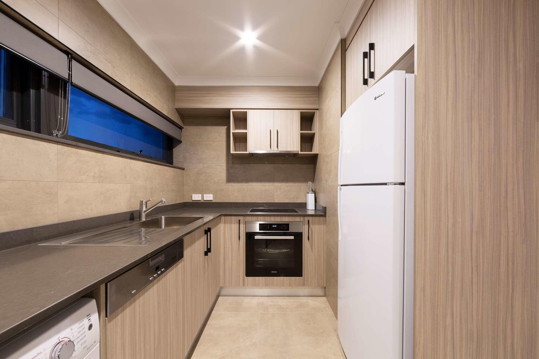 Modern kitchen with white cabinets, wood accents, black countertops, and a refrigerator