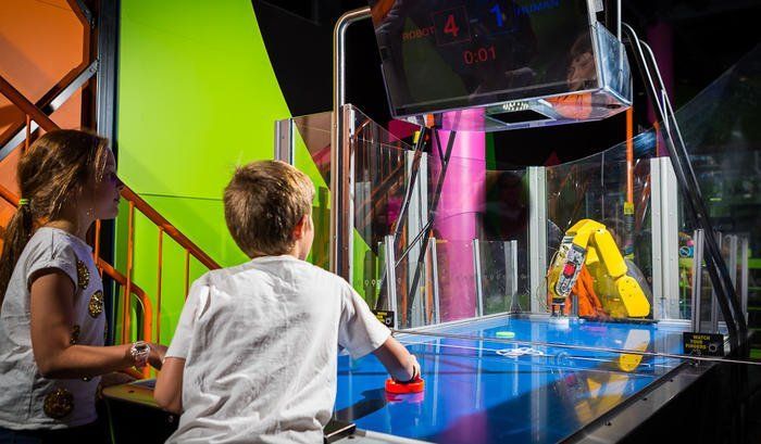 Children playing a water arcade game with colorful lights and a blue table in an indoor arcade