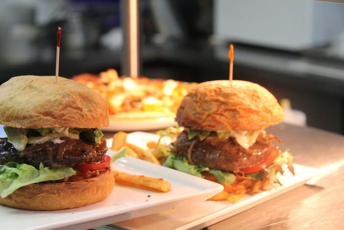 Two burgers on white plates with fries on a table in a restaurant