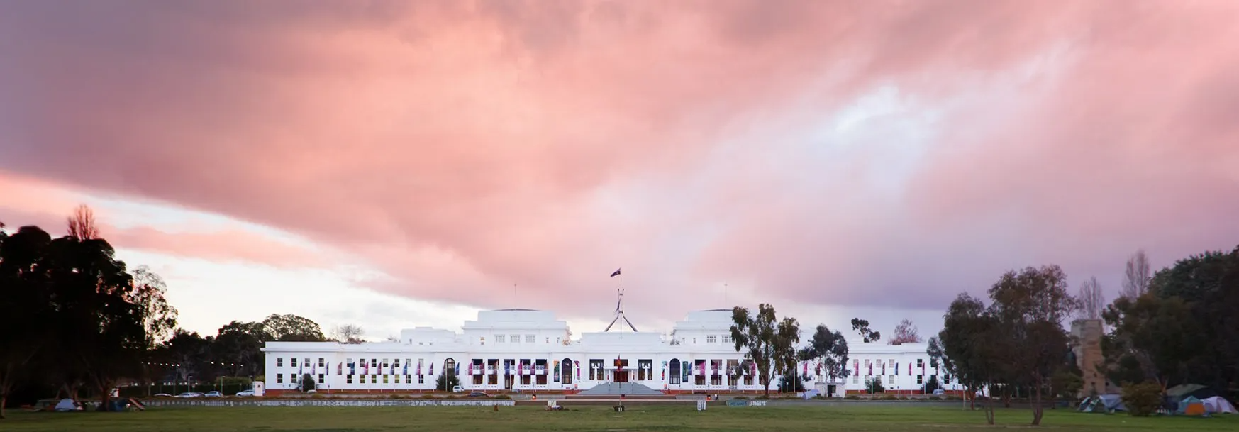 White building on a grassy field under a pink sunset sky