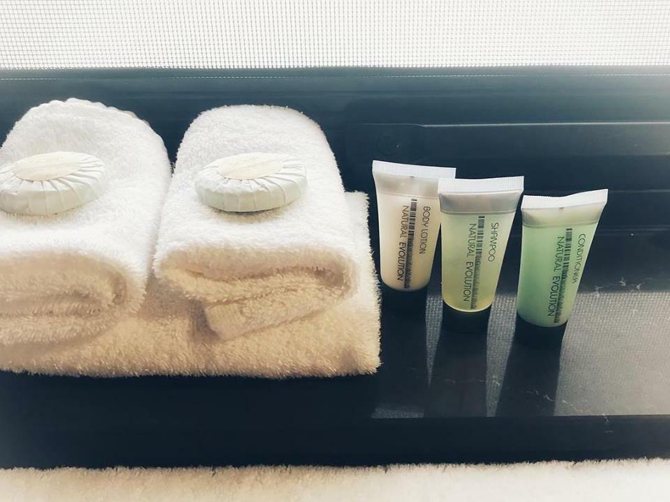 Towels and toiletries neatly arranged on a dark countertop near a window.