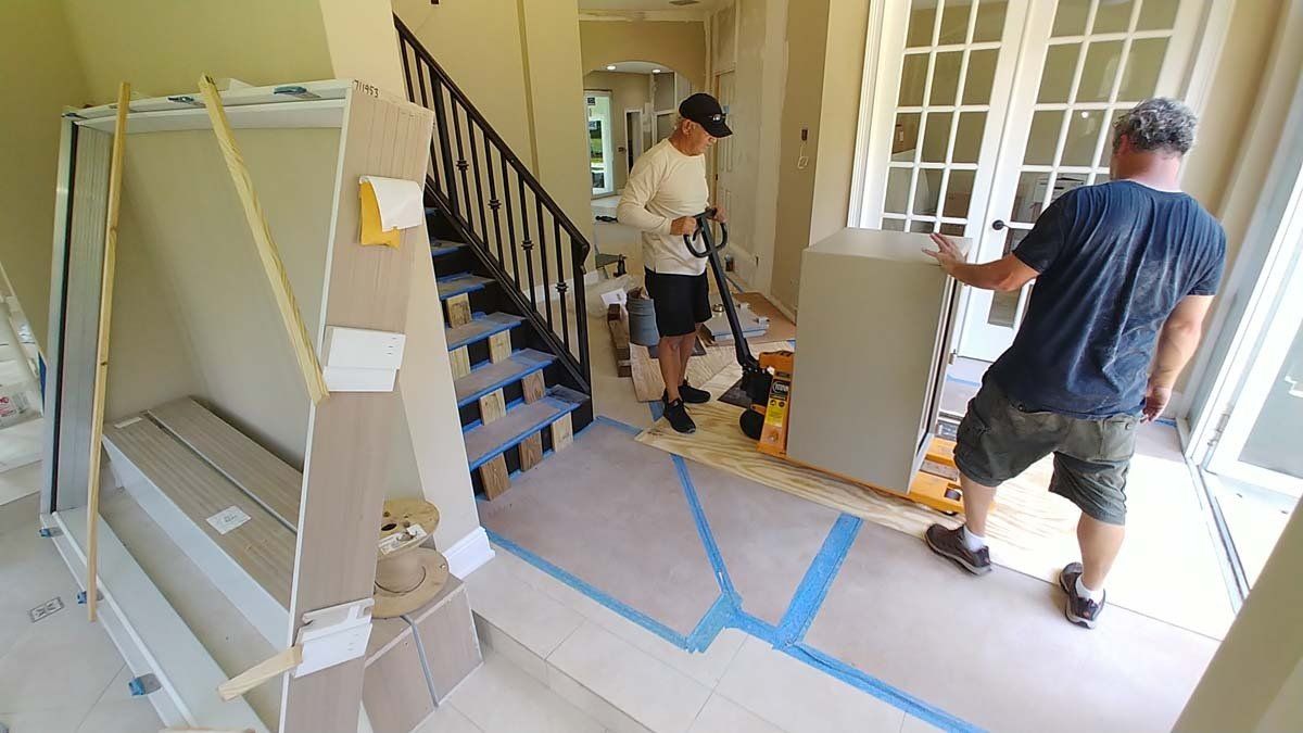 Workers carrying boxes through a taped-off room during home renovation