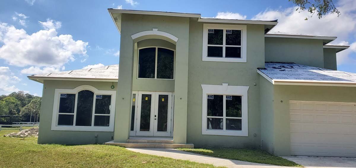 Modern two-story white house with arched entry and attached garage on a grassy lot