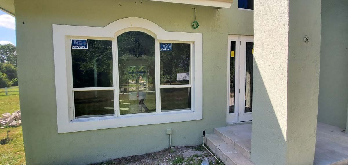 Cream-colored house exterior with white-trimmed windows and a small porch step, lit by sunlight