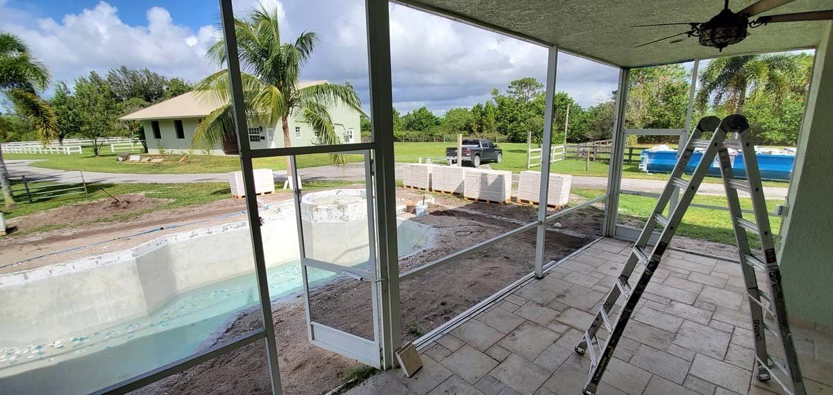 Covered patio overlooking a backyard pool with sliding glass doors and patio furniture.