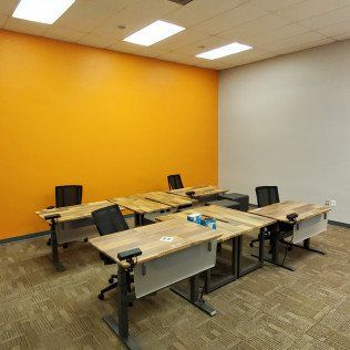 Empty classroom with orange and white walls, tables, chairs, and ceiling lights.