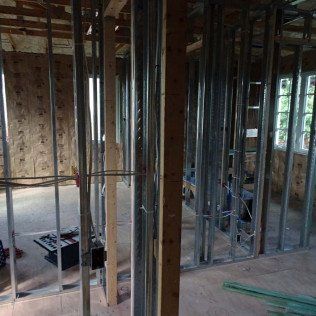 Framed room under construction with exposed studs, wiring, and plywood walls
