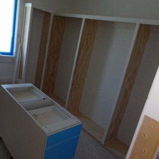 Partially assembled white and blue cabinet frame in a room with a window