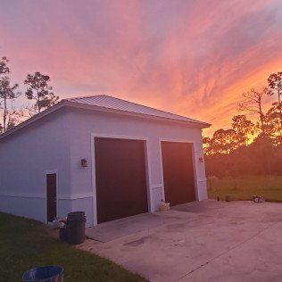 White two-car garage at sunset with a pink-orange sky and concrete driveway