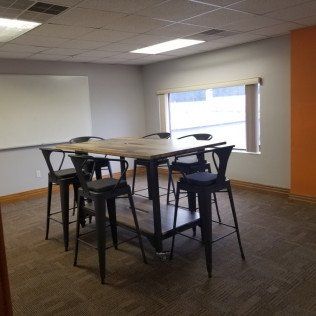 High-top table with stools in a sparse office room near a window