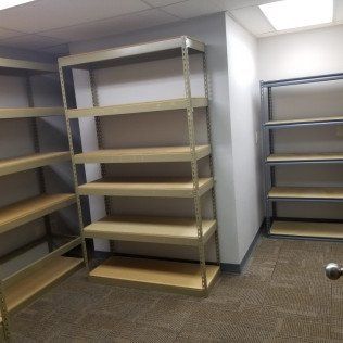 Empty storage room with metal shelving units and beige carpet flooring.