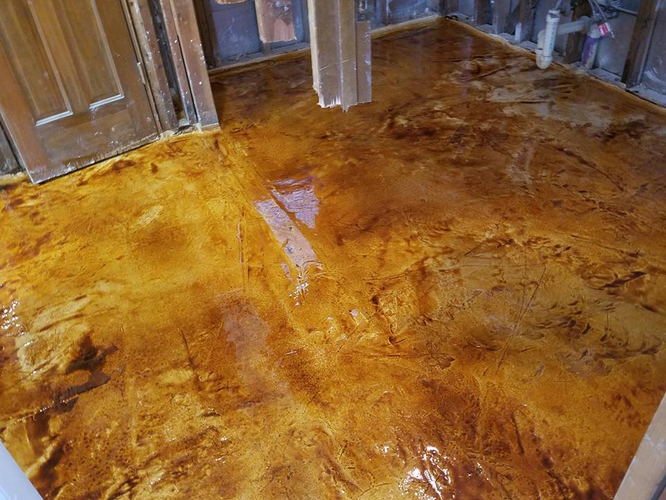 Shiny amber stained floor in a room with wooden doors and walls, showing marbled wood grain.