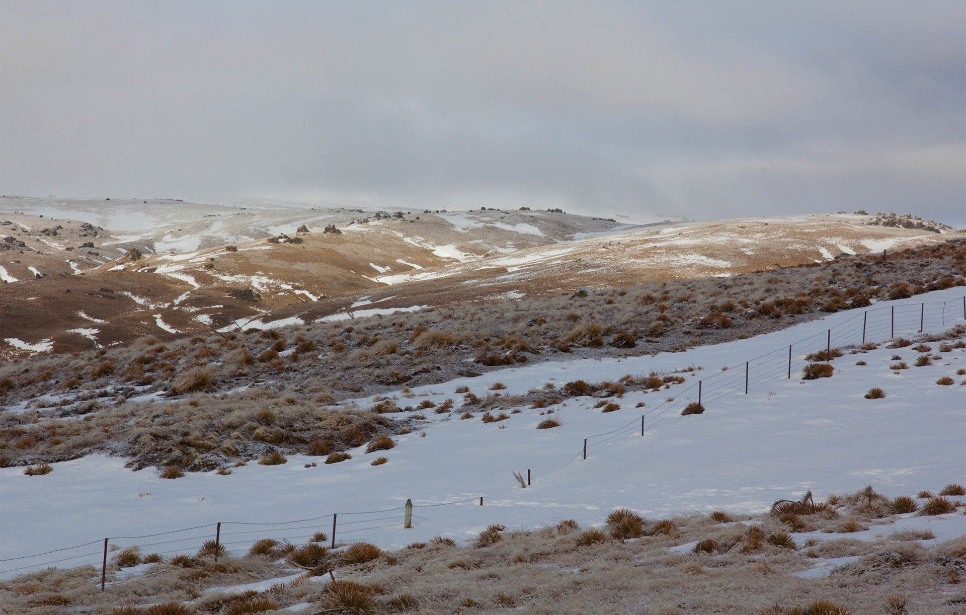 A snowy field with a fence in the foreground
