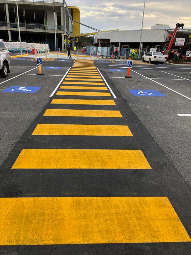 A yellow and black crosswalk in a parking lot