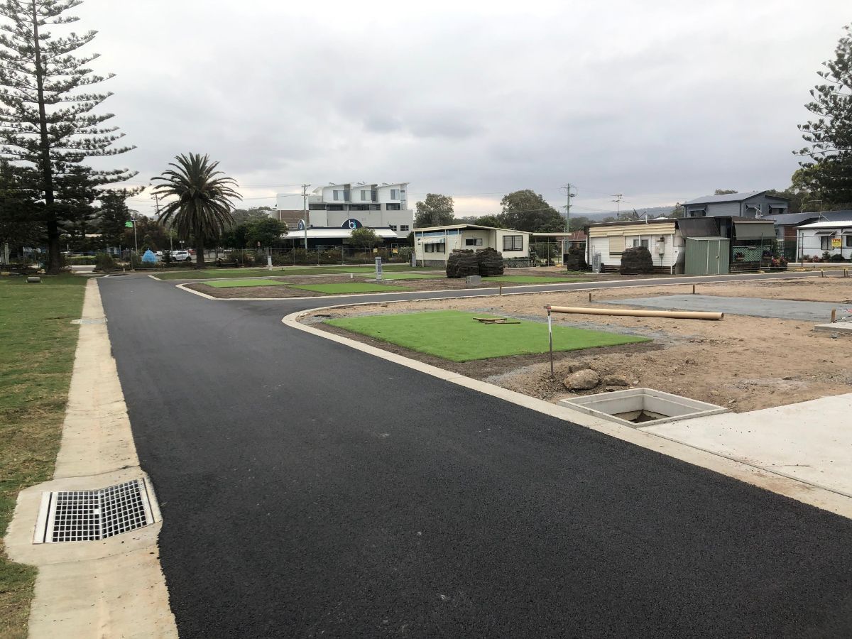 A road with a drain on the side of it going through a residential area.