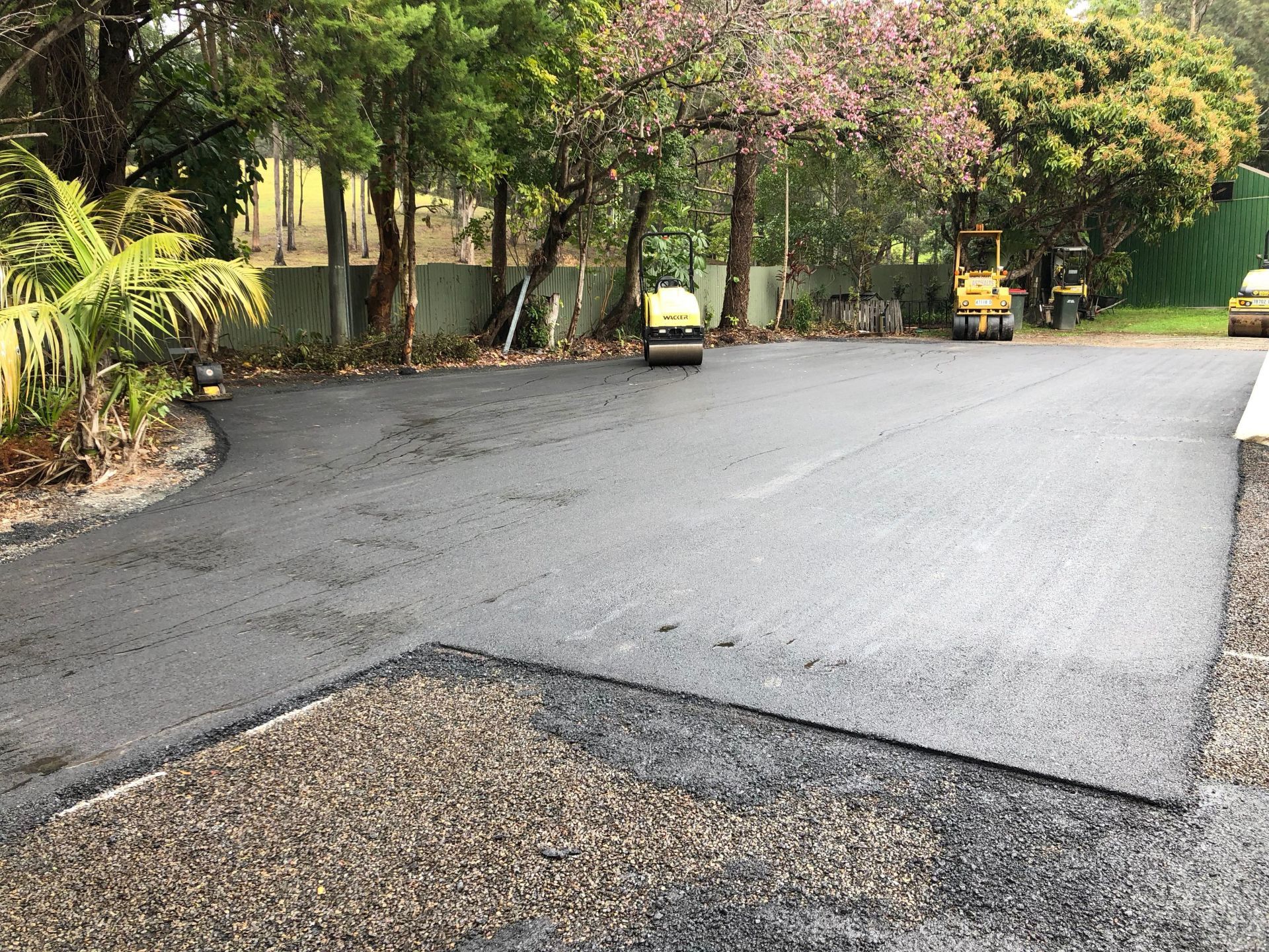 A row of rollers are rolling asphalt on a road.