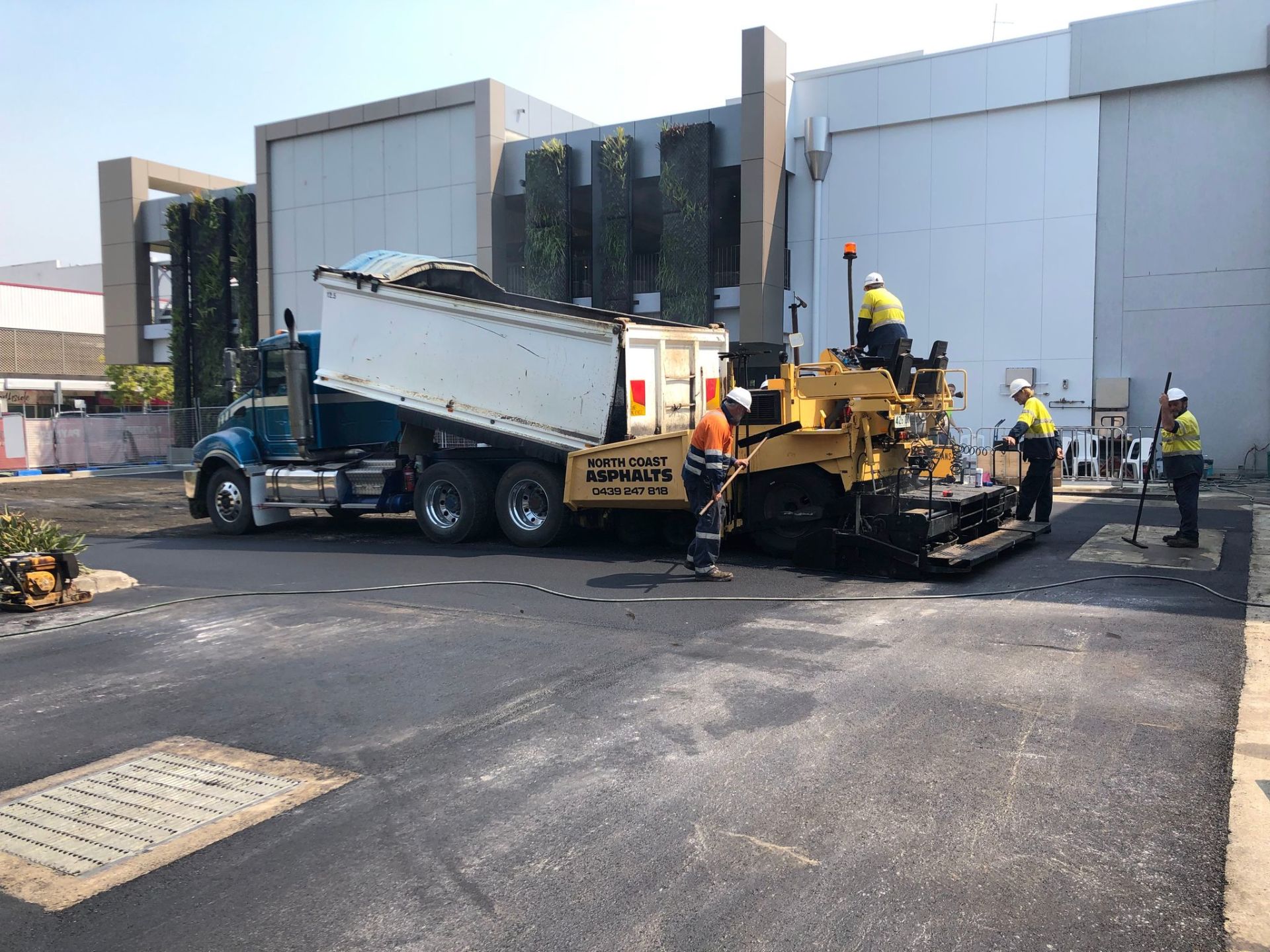 A dump truck is being loaded with asphalt in a parking lot.