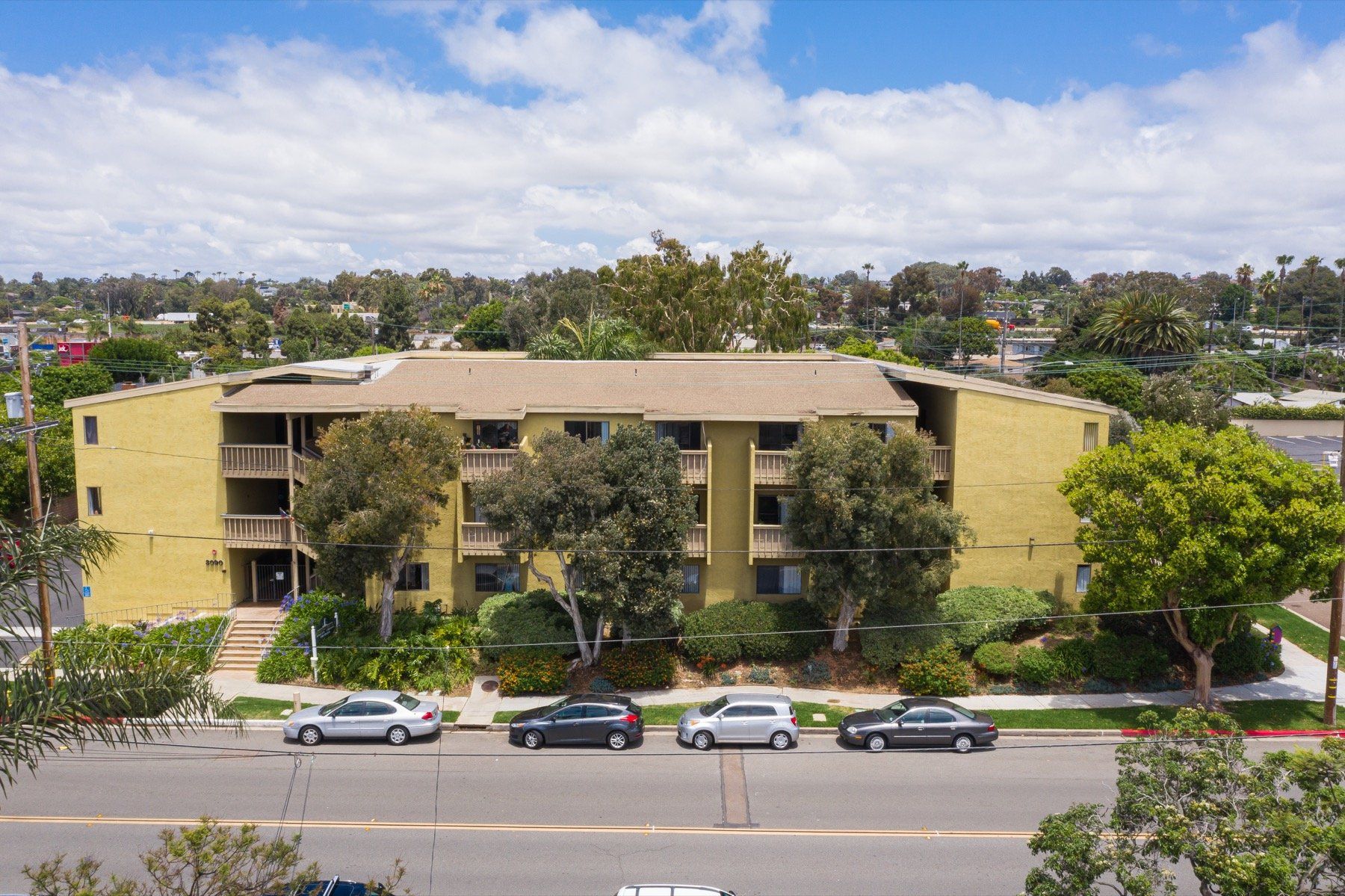 An aerial view of a large apartment building with cars parked in front of it.