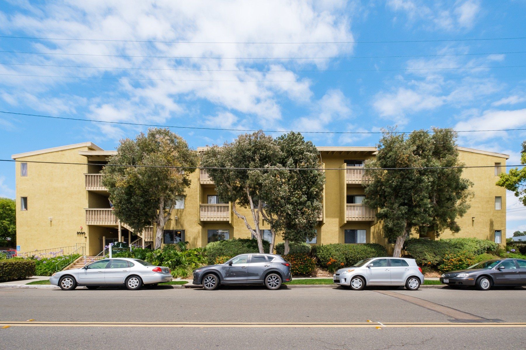 A row of cars are parked in front of a building.