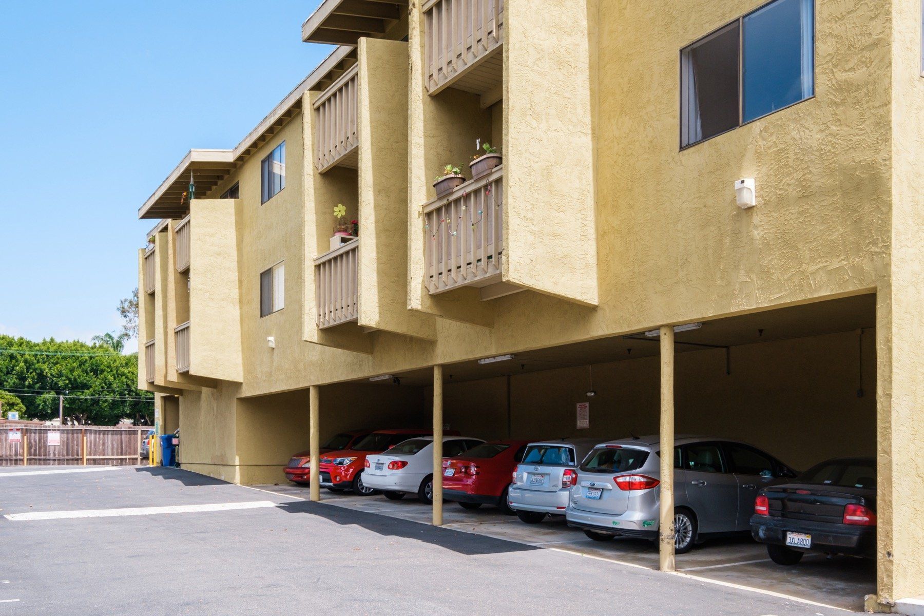 A row of cars are parked underneath a building