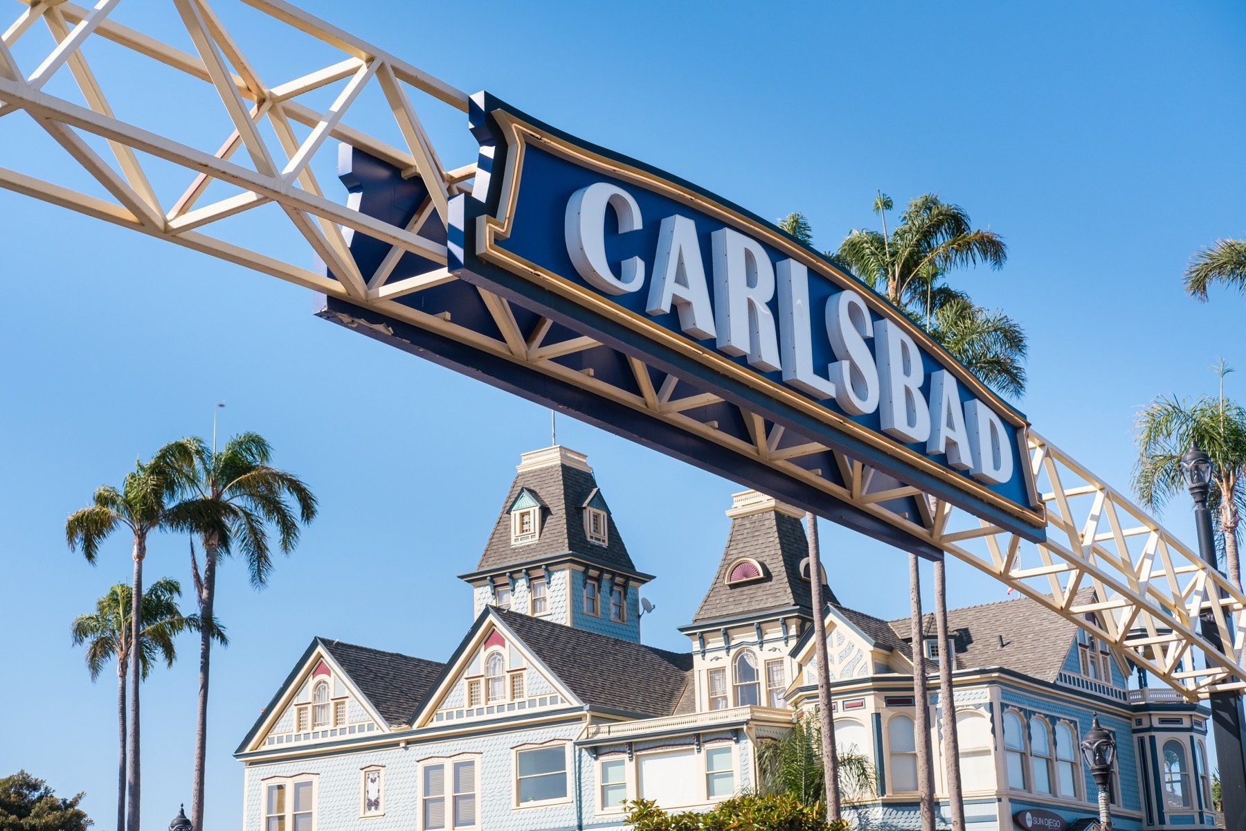 A carlsbad sign is hanging over a building with palm trees in the background.