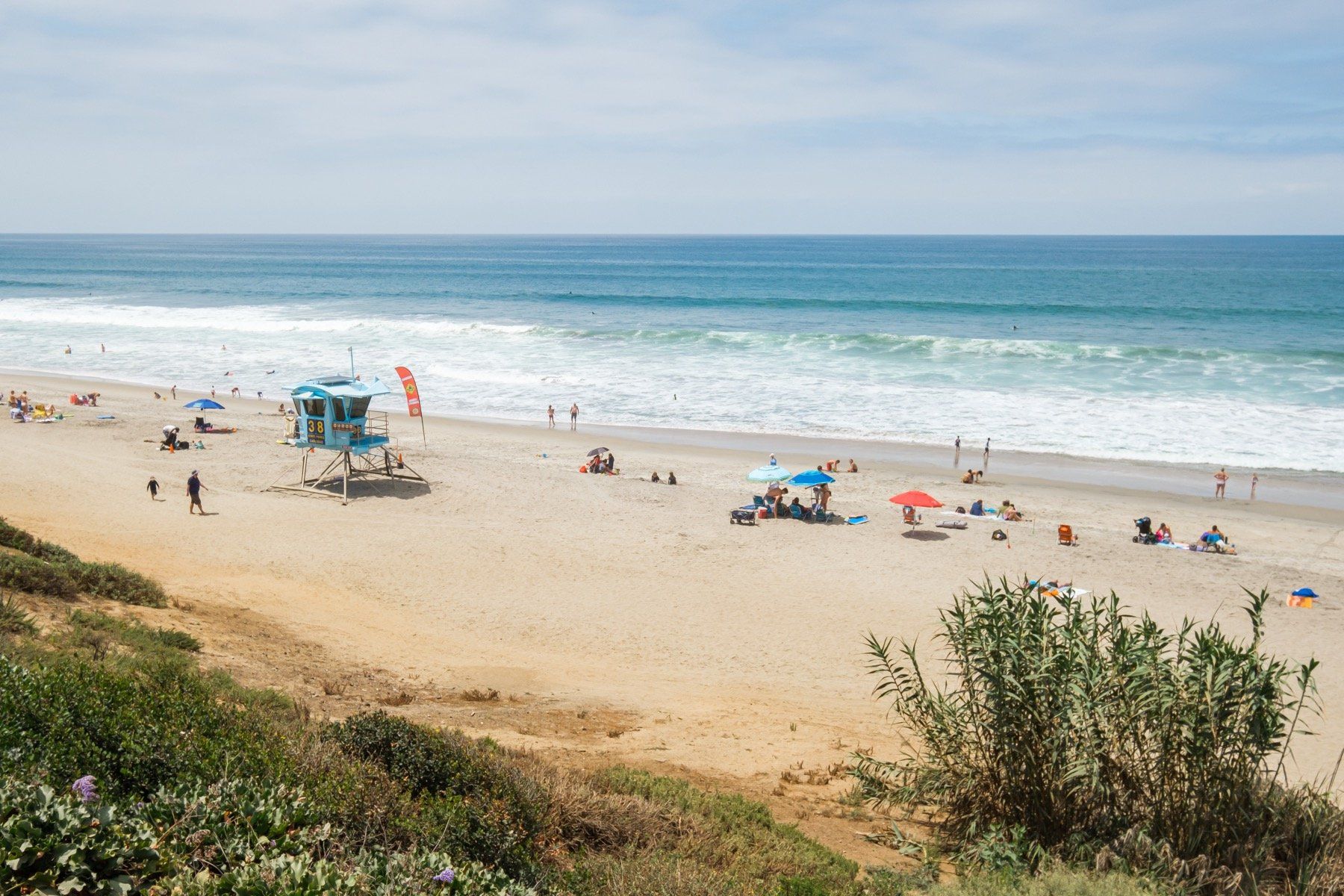 A beach with a lifeguard tower and a lot of people on it.