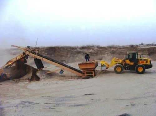Bulldozer y excavadora cargando una cinta transportadora de tierra colapsada en una cantera.