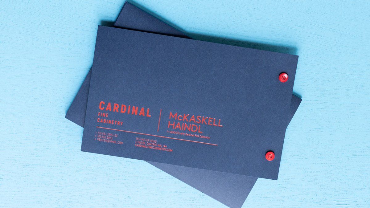 Dark blue card with red text. Two red pins hold the pages together.