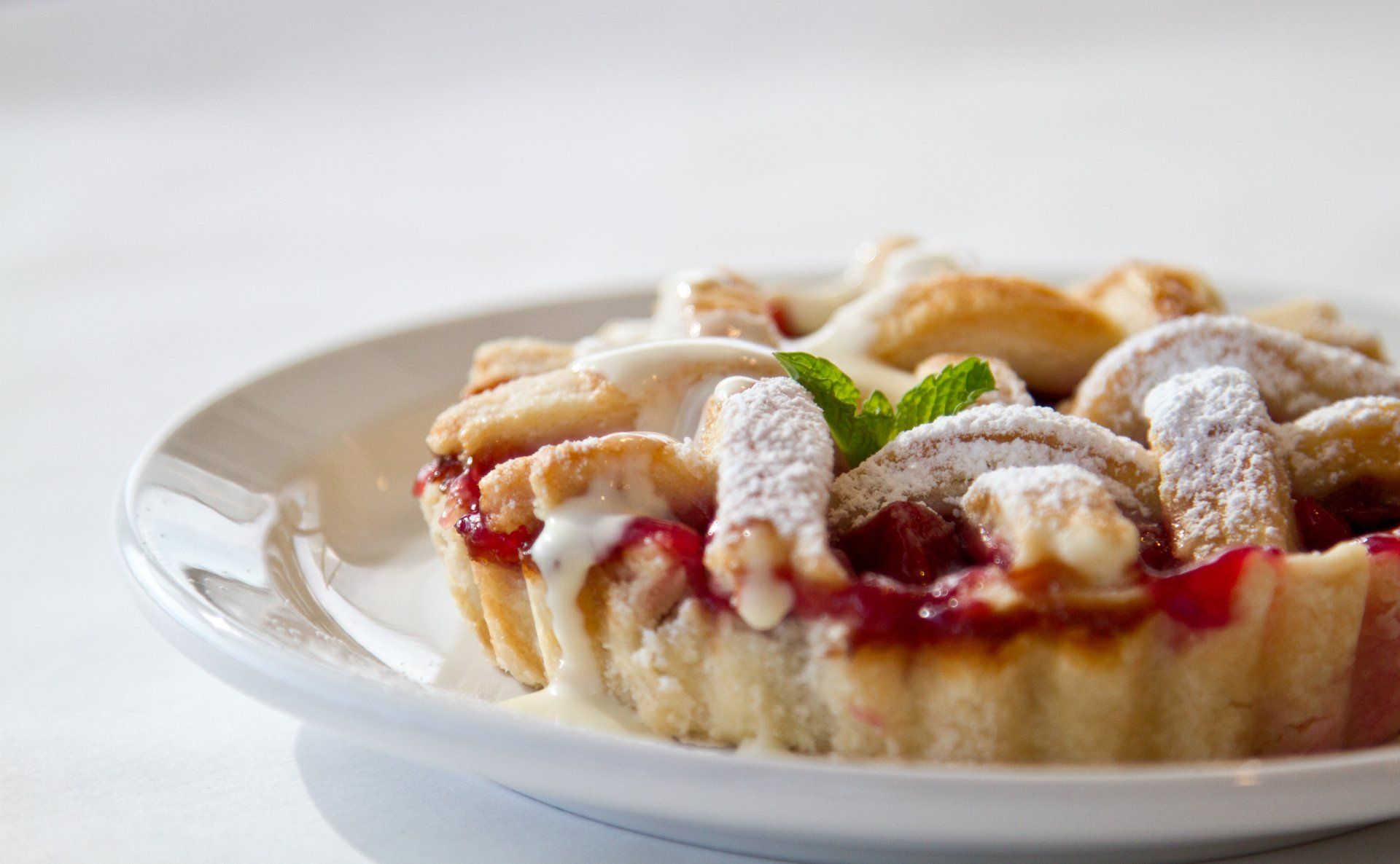 Cherry pie on a white plate, topped with lattice crust and powdered sugar.