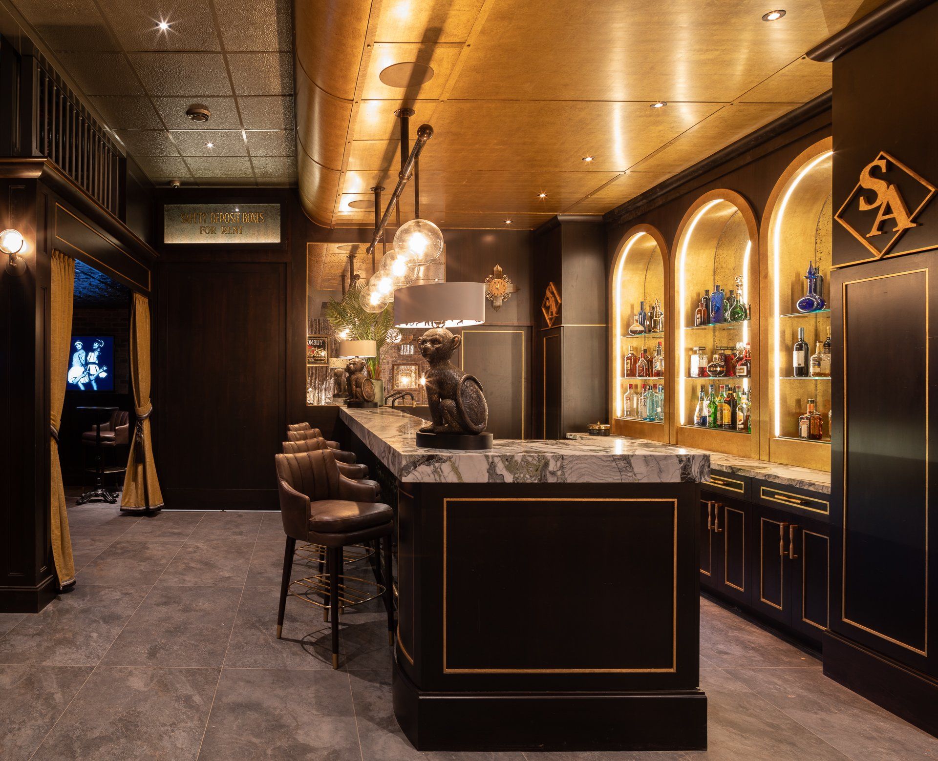 Interior of a dark bar with a marble-topped counter, shelves of liquor, and seating.
