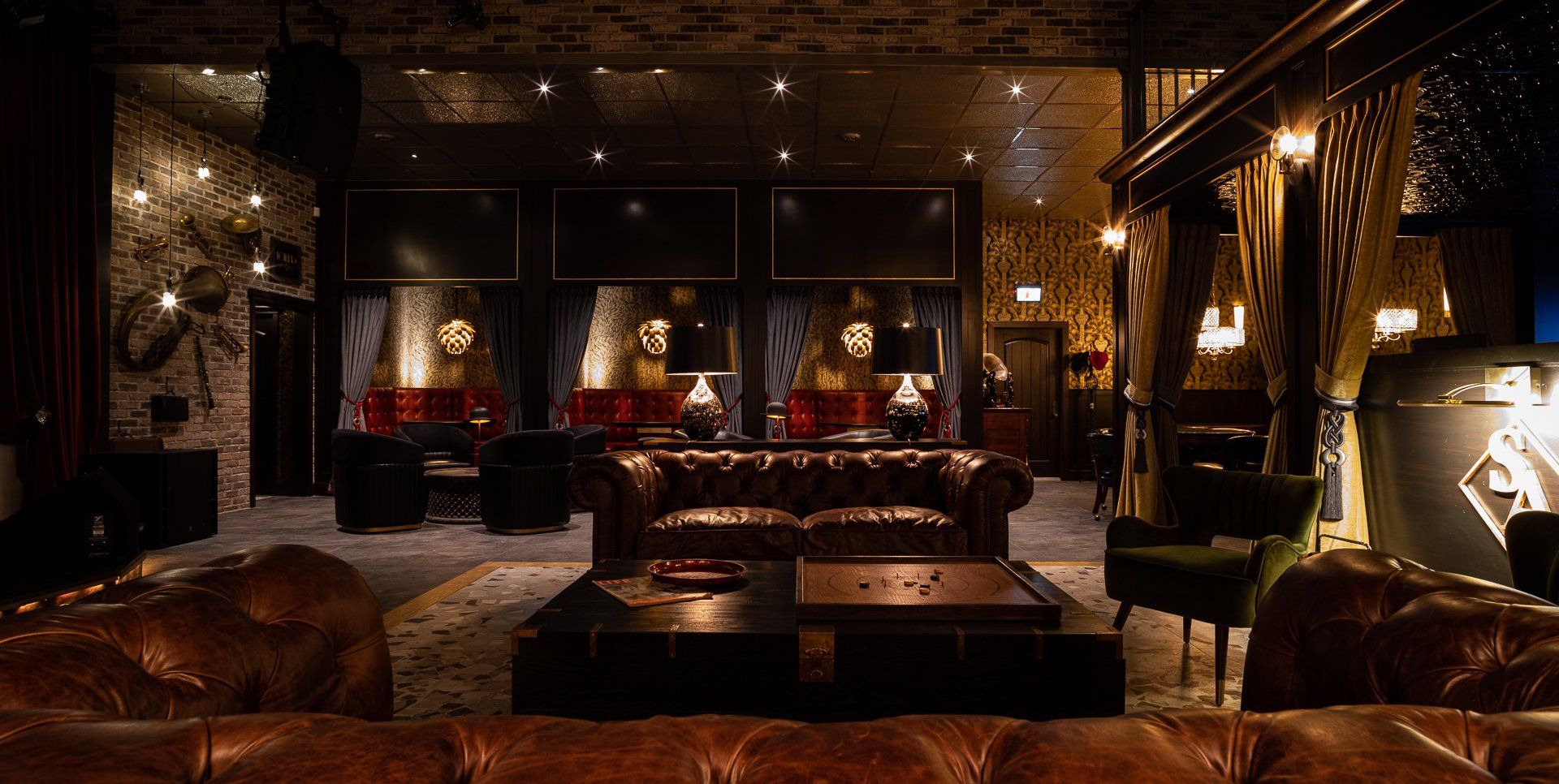 Dark, luxurious lounge with leather couches, dim lighting, and decorative wall art.