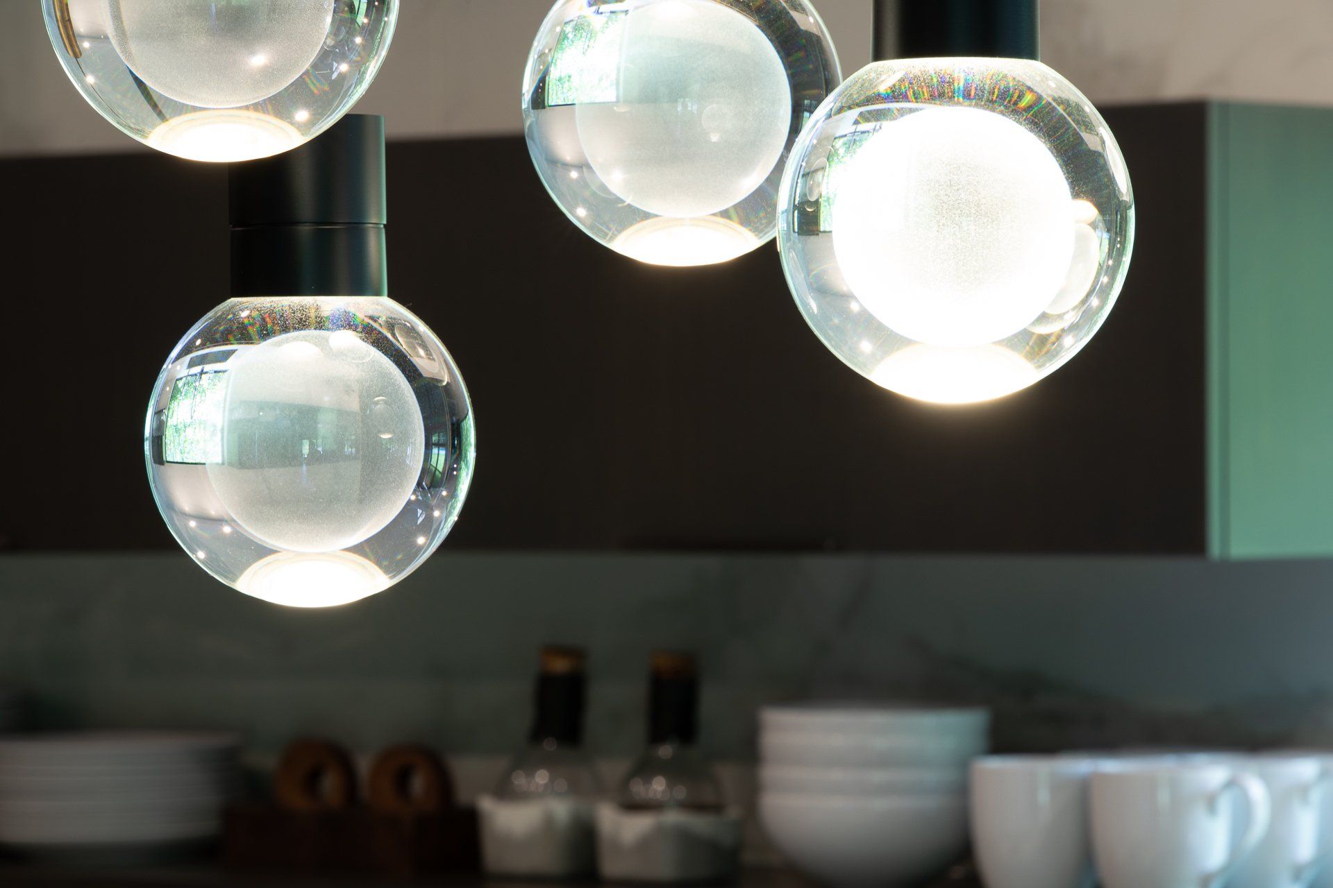 Four spherical glass pendant lights illuminating a kitchen countertop.