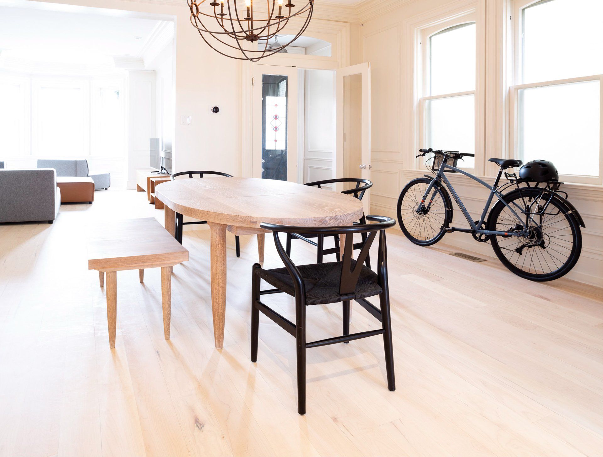 Light-filled dining room with wood table, chairs, and bicycle leaning against a window.