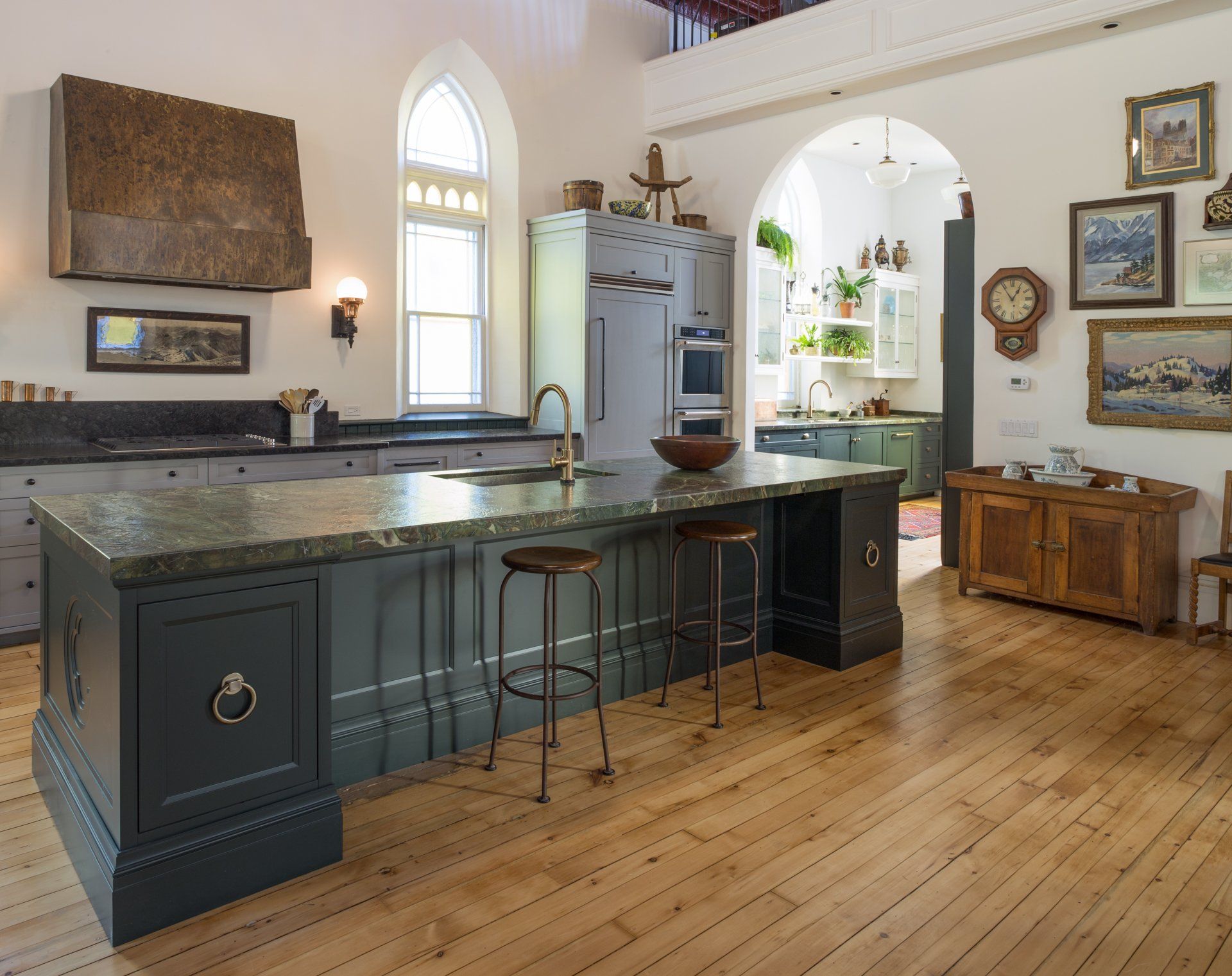 Spacious kitchen with island and bar stools, hardwood floors, and arched window.