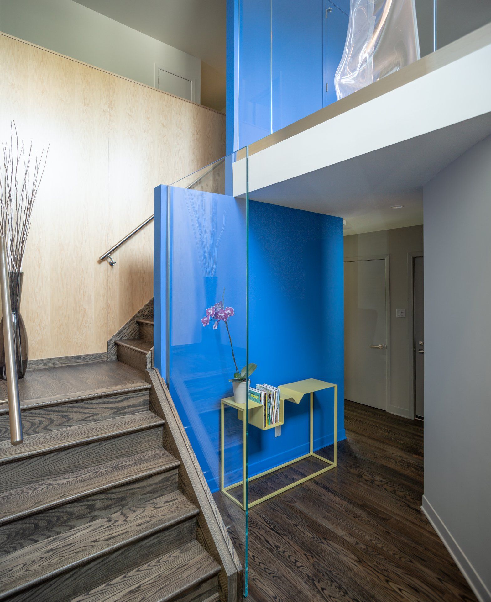 Staircase with wooden steps and a blue accent wall. A small yellow table holds toiletries.