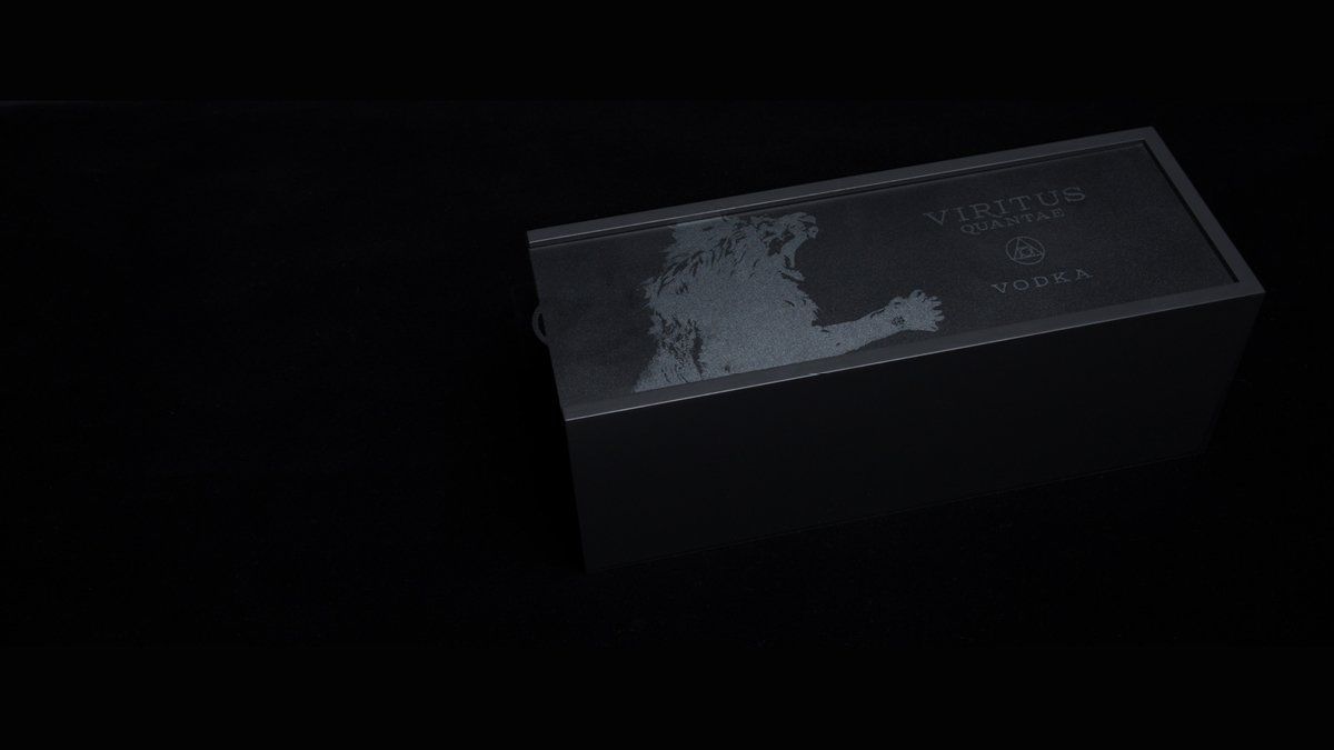 A dark rectangular metallic box with a wet, textured top surface against a black background.