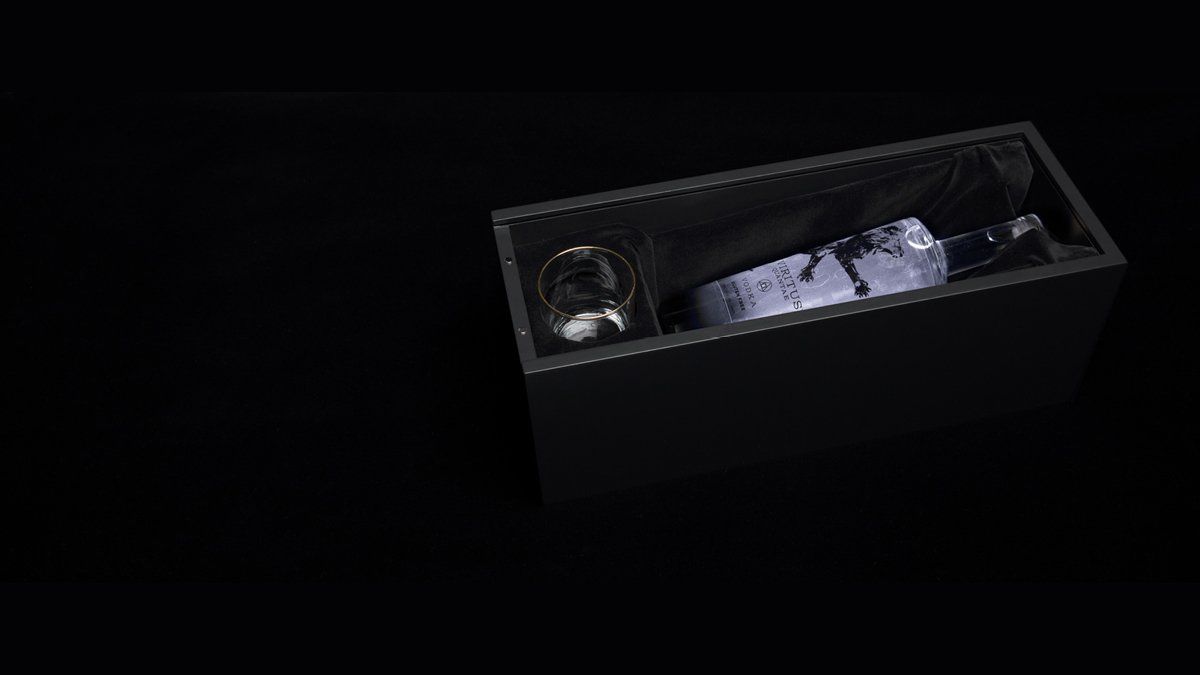 Black rectangular box with a bottle and a glass inside. Dark setting.