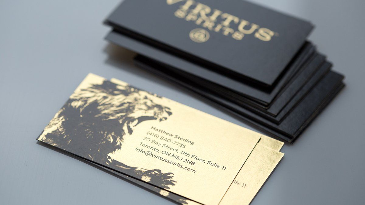 Business cards with gold text on dark grey, stacked.