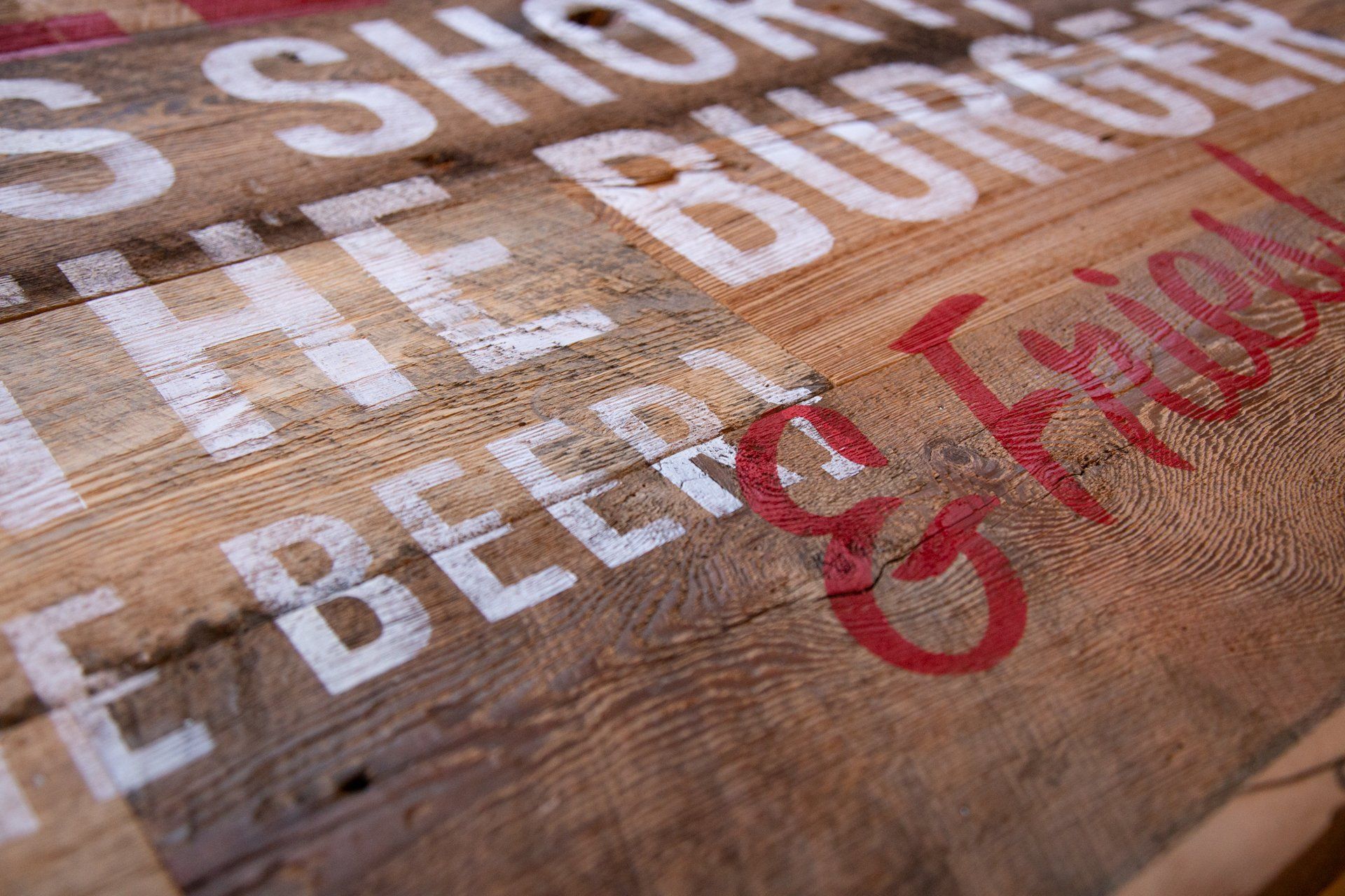 Wooden sign with white and red lettering: 