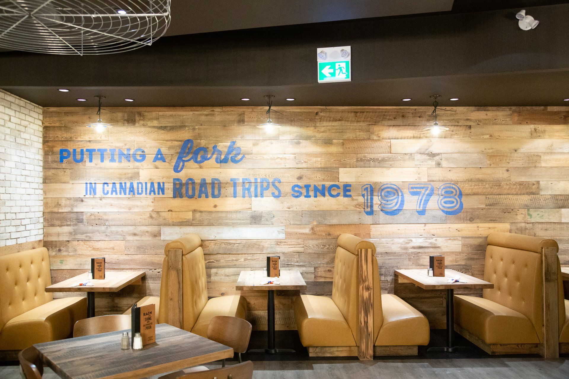 Restaurant interior with booths and tables. A wooden wall with text: 