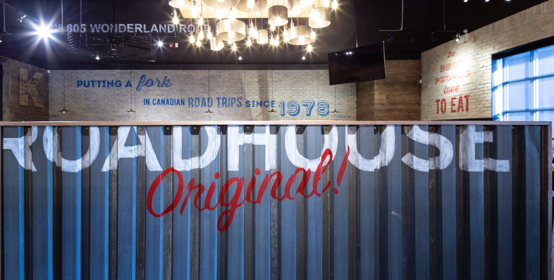 Roadhouse Original restaurant entrance with a painted sign, brick wall, and overhead lighting.