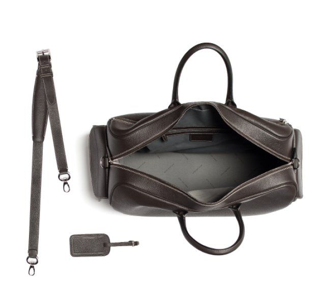 Dark brown leather duffel bag, open, with shoulder strap and luggage tag, on white.
