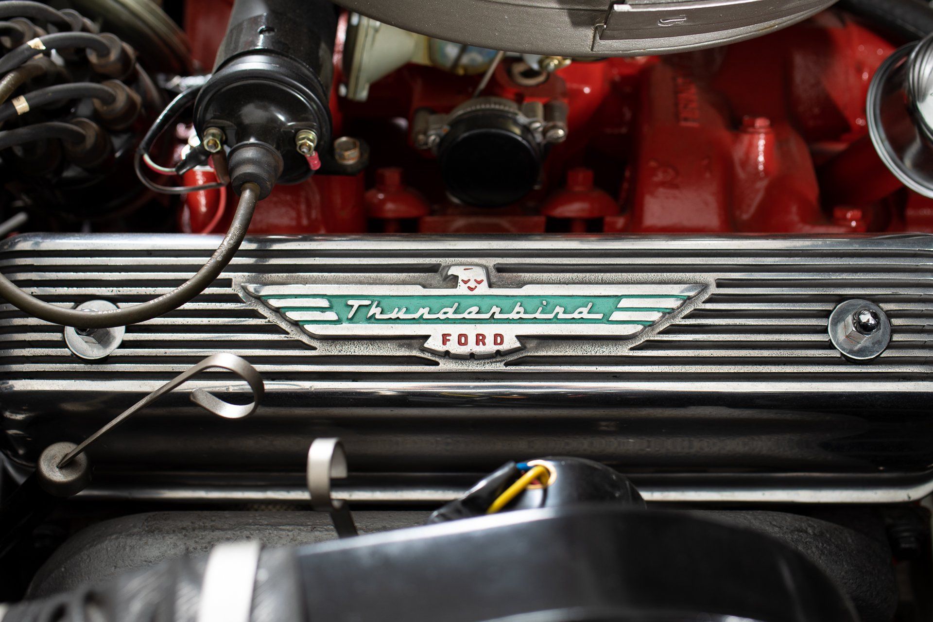 Close-up of a classic Ford Thunderbird engine with the logo prominently displayed in teal and silver.