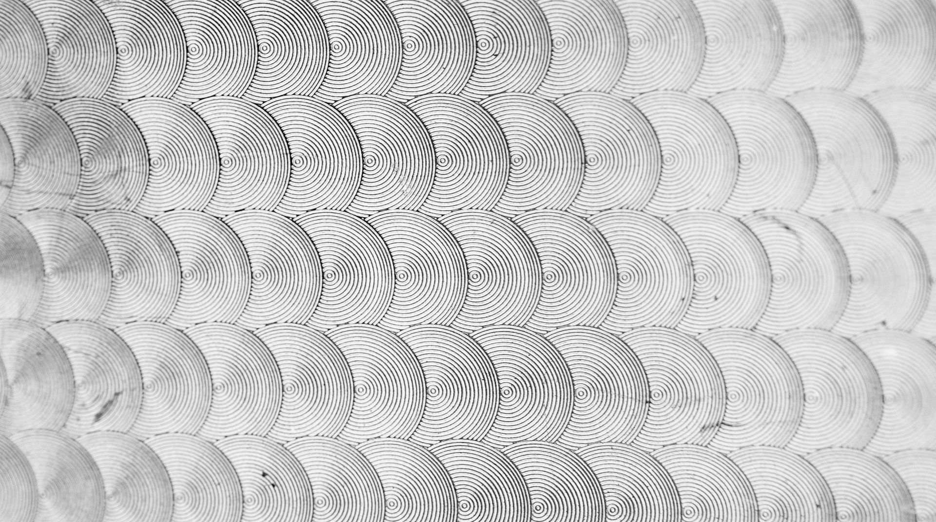 Repeating pattern of textured half-circles, each with a striped, abstract design; gradient from dark to light.
